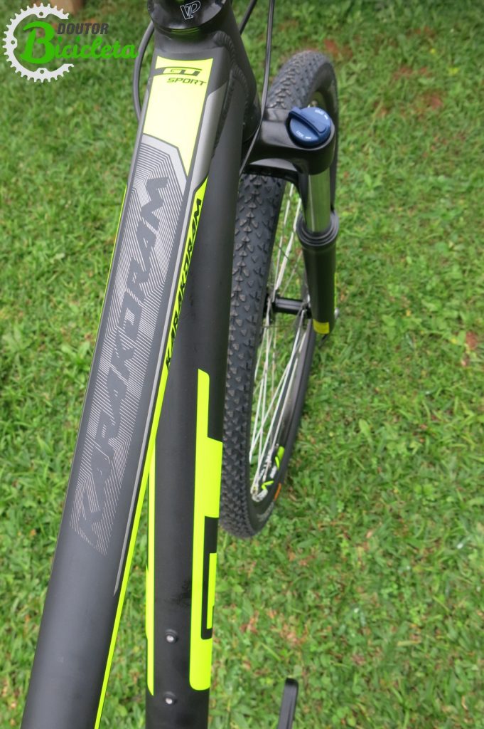 Detalhe das cores vibrantes da bicicleta; selim possui faixa com mesmo tom neon 