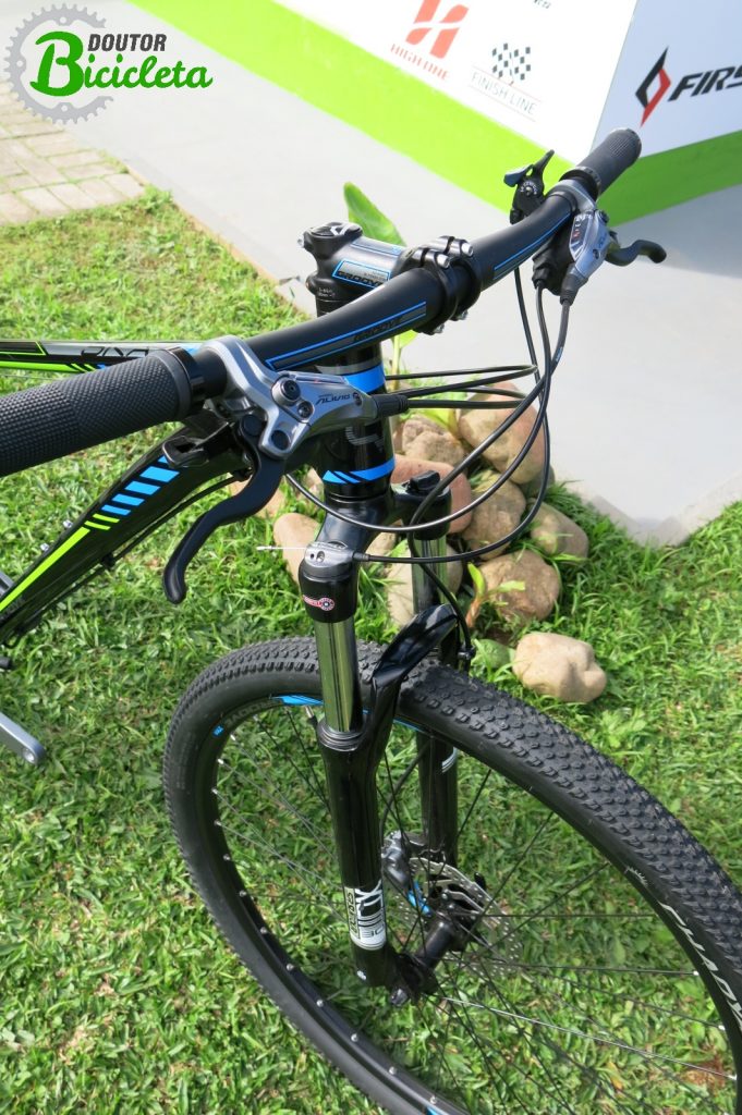 Destaque: Trocadores e manetes Shimano Alivio, freio a disco hidráulico, suspensão com trava no guidão, aro de 29", pneu Chaoyang e detalhes no avanço e guidão nas cores da bicicleta.