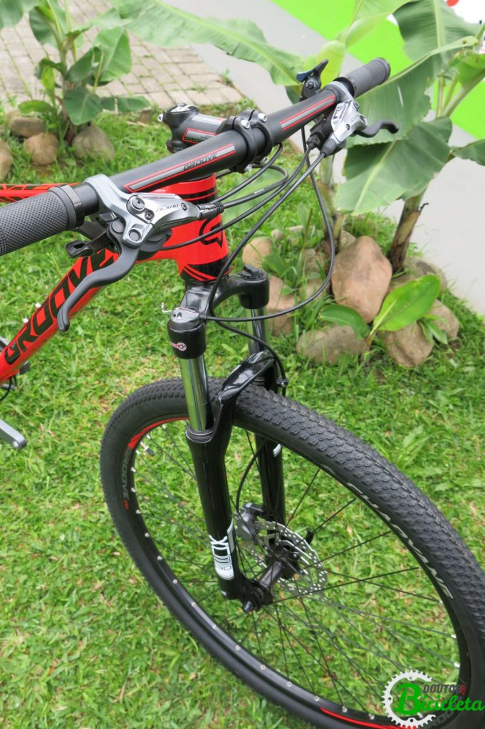 Suspensão dianteira SR Suntour XCM 100mm com trava no guidão, trocadores de marcha com manete de freio intergrado Shimano Alivio 2-way system, Aros de 29", detalhes na cor do quadro no aro, avanço e guidão.